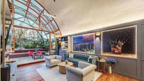 Un soggiorno moderno con soffitto in vetro, vista sulla città e un'accogliente area salotto.