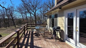 Una terraza de madera con mobiliario exterior, una parrilla y una chimenea de piedra.