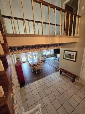 A spacious living area with a high ceiling and a staircase leading to an upper level. - Charming 3-bedroom farmhouse with large front and back decks. Fenced in backyard (Warrensburg)