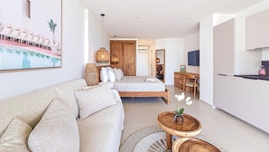 Una habitación moderna y luminosa con sofá, cama, comedor y cocina.