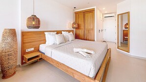 Un dormitorio moderno con una cama de madera, ropa de cama blanca, una lámpara de pie tejida y un espejo grande.