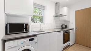A compact kitchen with a microwave, sink, dishwasher, and oven. - Modern Flat in Prime Location (Greater London)