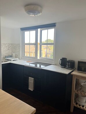 Eine kleine Küche mit Fenster, einer Mikrowelle, einem Toaster und einem Spülbecken.