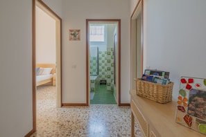 A hallway with a bed, a wicker basket with cards, and a mirror with a decorative frame. - Cookie House in Perledo (Perledo)