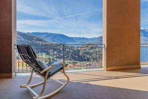 A balcony with a rocking chair, offering a view of mountains and a lake. - Cookie House in Perledo (Perledo)