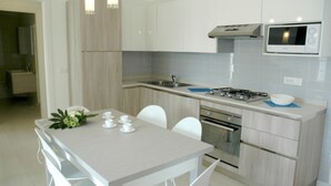 A modern kitchen with a central island, stainless steel appliances, and a microwave. - Lovely Villa in Lignano Pineta (Lignano Sabbiadoro)