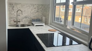 A modern kitchen with a marble backsplash, a built-in sink, and a window with a view of the neighborhood. - Spacious Ensuite Room in Clapham (Greater London)