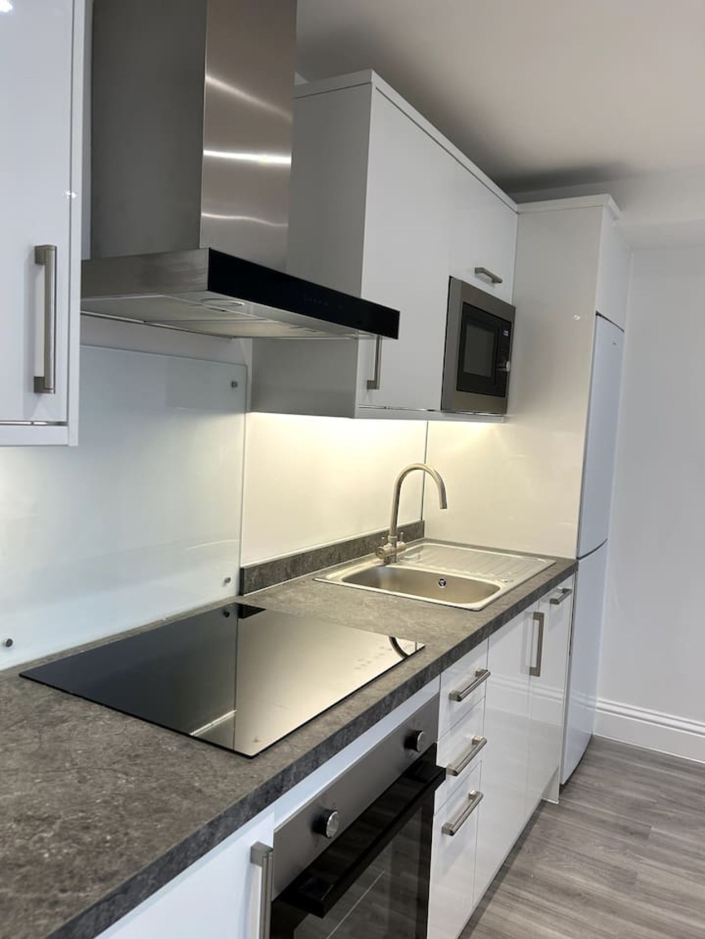 Una cocina moderna con electrodomésticos de acero inoxidable, un lavamanos doble y un microondas.