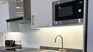 Una cocina moderna con electrodomésticos de acero inoxidable, horno empotrado, lavavajillas y microondas.