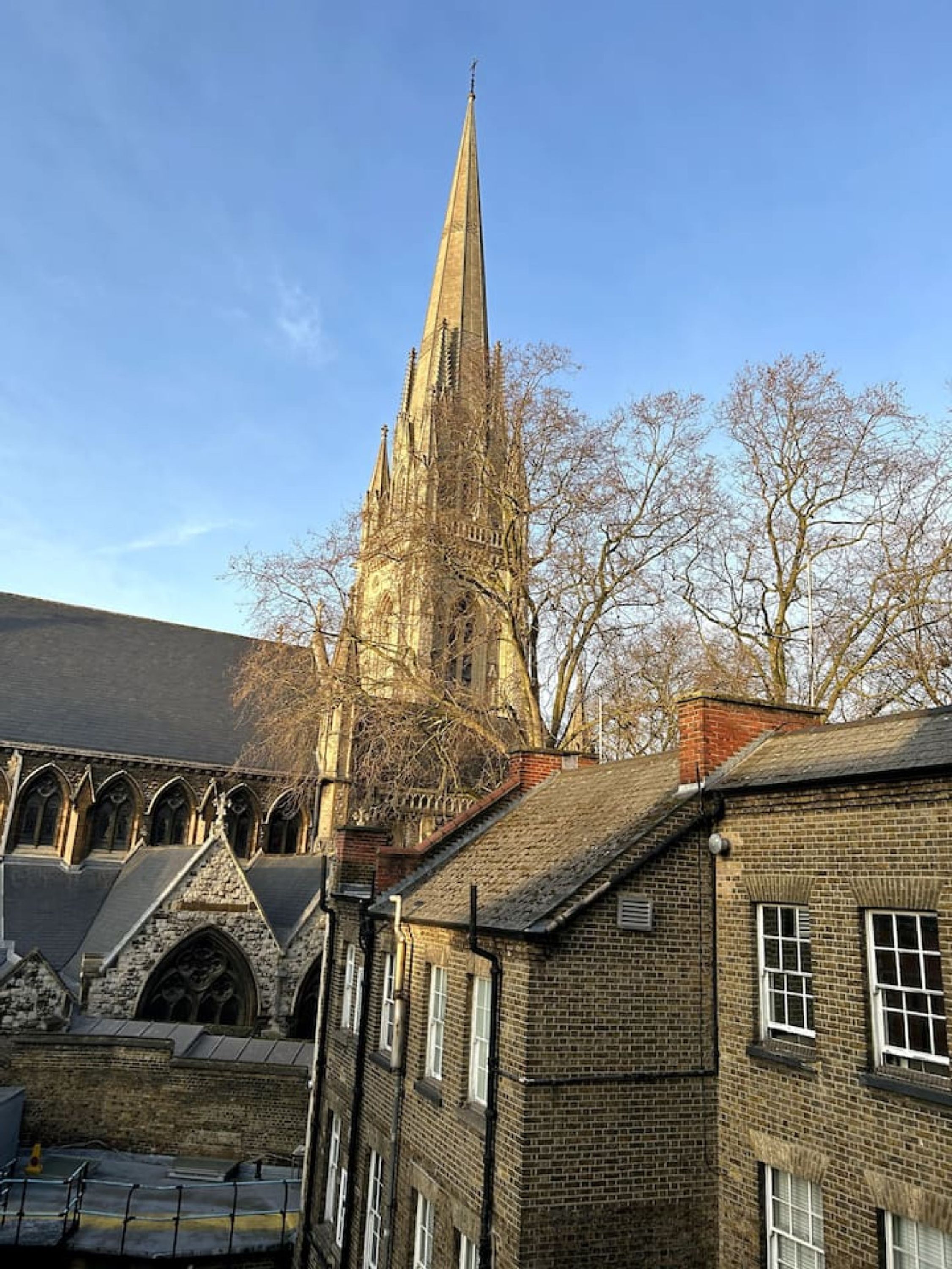Eine historische Kirche mit einem hohen Turm und angrenzenden Backsteingebäuden.