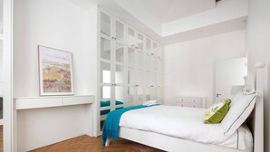A bedroom with a bed, a wardrobe, a bedside table, and a painting on the wall. - Charming Mews House in Kensington (Greater London)