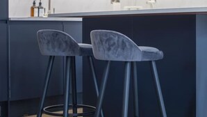 Eine moderne Küche mit zwei Barhocker, einem Spülbecken und einer Arbeitsplatte.