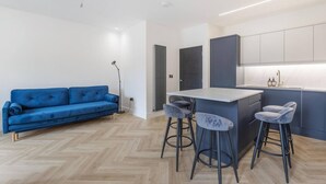 Eine moderne Küche mit Barbereich, einem blauen Sofa und zwei Barhocker.