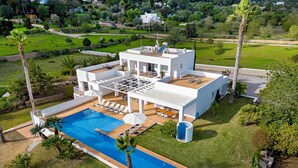 Una villa moderna con piscina, mobiliario de exterior y un jardín exuberante.