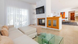 Una sala de estar moderna con sofá, mesa de centro de vidrio y chimenea.