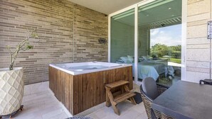 Ein modernes Badezimmer im Freien mit einer Holzwanne, einem kleinen Holzschemel und einem Korbstuhl.