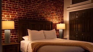 A bed with a wooden headboard, two bedside lamps, and a brick wall. - Old City Loft | Knoxville (Knoxville)