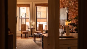 A spacious room with a wooden floor, a dining area with chairs and a table, and a kitchen area with cabinets and a hanging light fixture. - Old City Loft | Knoxville (Knoxville)