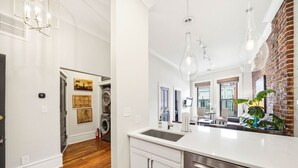 A modern kitchen with stainless steel appliances, a white countertop, and a brick accent wall. - Old City Loft | Knoxville (Knoxville)