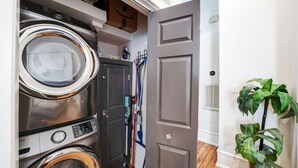 A laundry room with stacked washers and dryers, a door, and a potted plant.