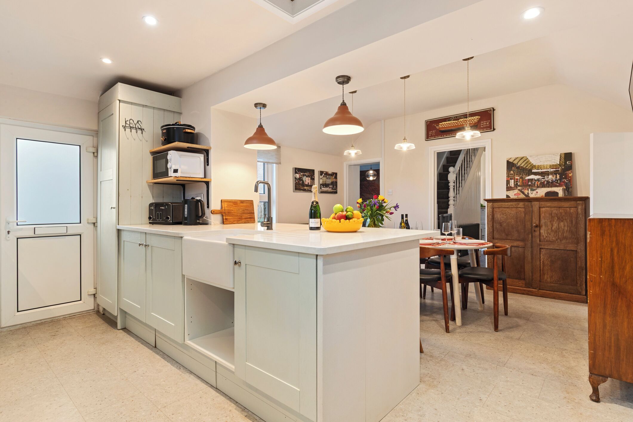 A modern kitchen with a central island, pendant lighting, and a dining area with a wooden table and chairs.