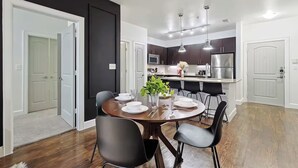 Una cucina moderna con mobili scuri, elettrodomestici in acciaio inossidabile e lampade a sospensione.