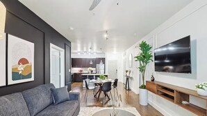 Un soggiorno moderno con un divano grigio, un'area pranzo con un tavolo rotondo e una cucina sullo sfondo.