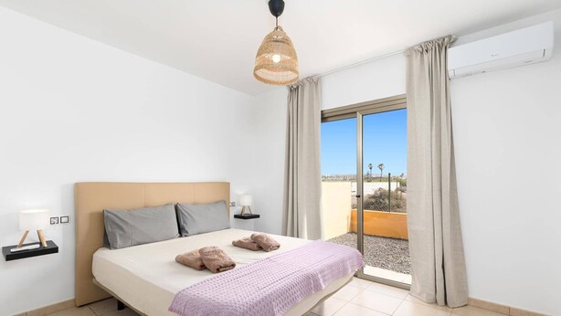 Une chambre d’hôtel avec un lit, une lampe de chevet, une fenêtre avec des rideaux et une vue sur l’extérieur.