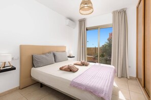 Een hotelkamer met een bed, nachtkastje, lamp en uitzicht op het landschap.
