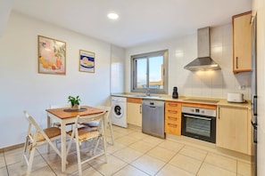 Una cocina compacta con ventana, lavadora, lavavajillas y horno empotrado.