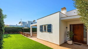A modern house with a well-maintained lawn, a wooden fence, and a potted plant near the entrance. - Villa Dreams by Villa Plus (Los Delfines)