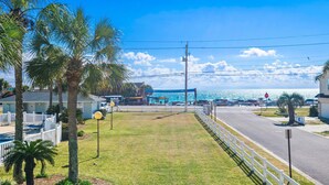 A coastal road with a white fence, palm trees, and a view of the ocean. - Tradewinds Condominium #28- At the Beach! (Miramar Beach)