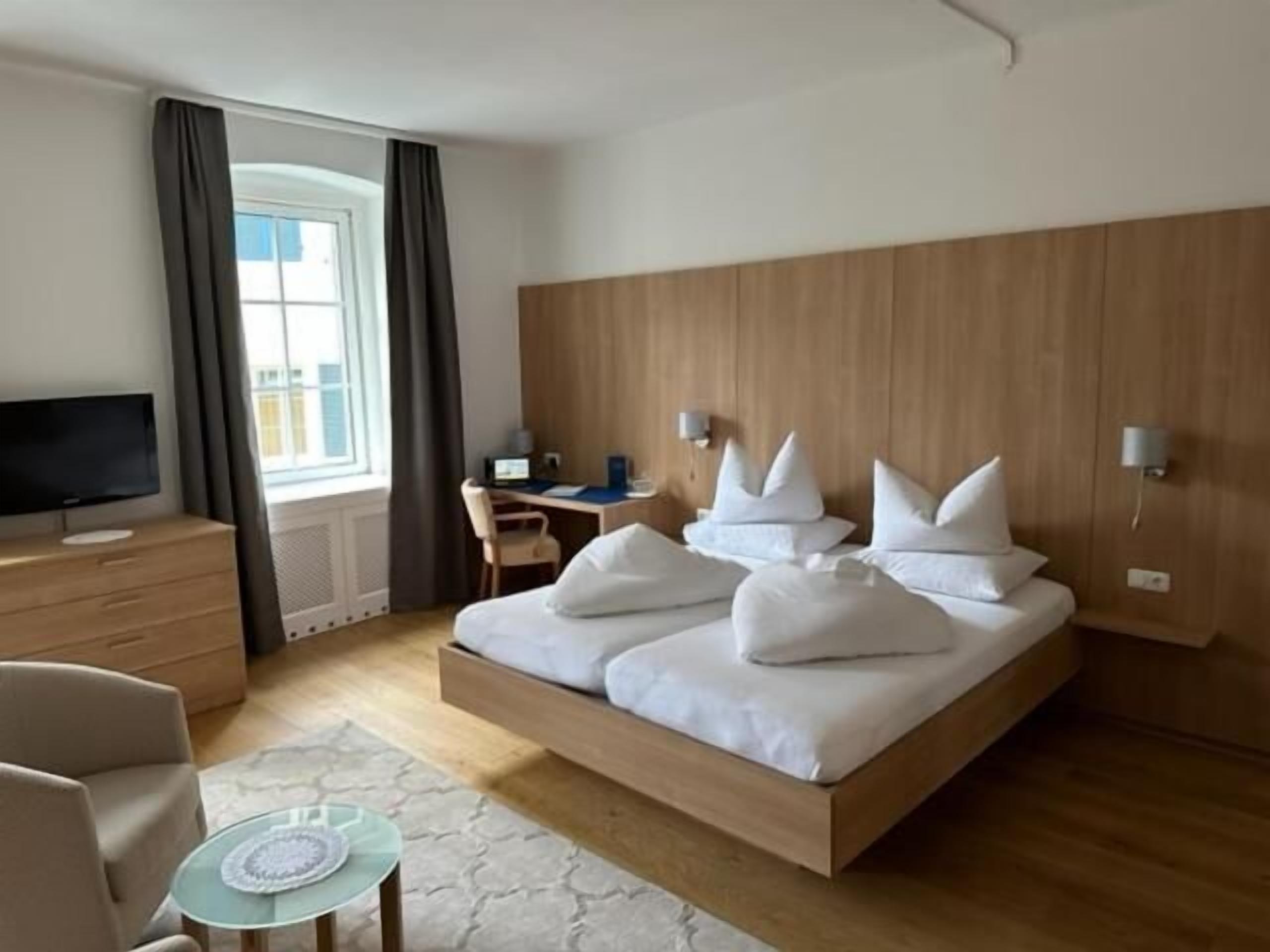 Una habitación de hotel moderna con una cama grande, un escritorio, un televisor y vistas a la ciudad.