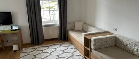Habitación compacta con cama, escritorio y televisión.