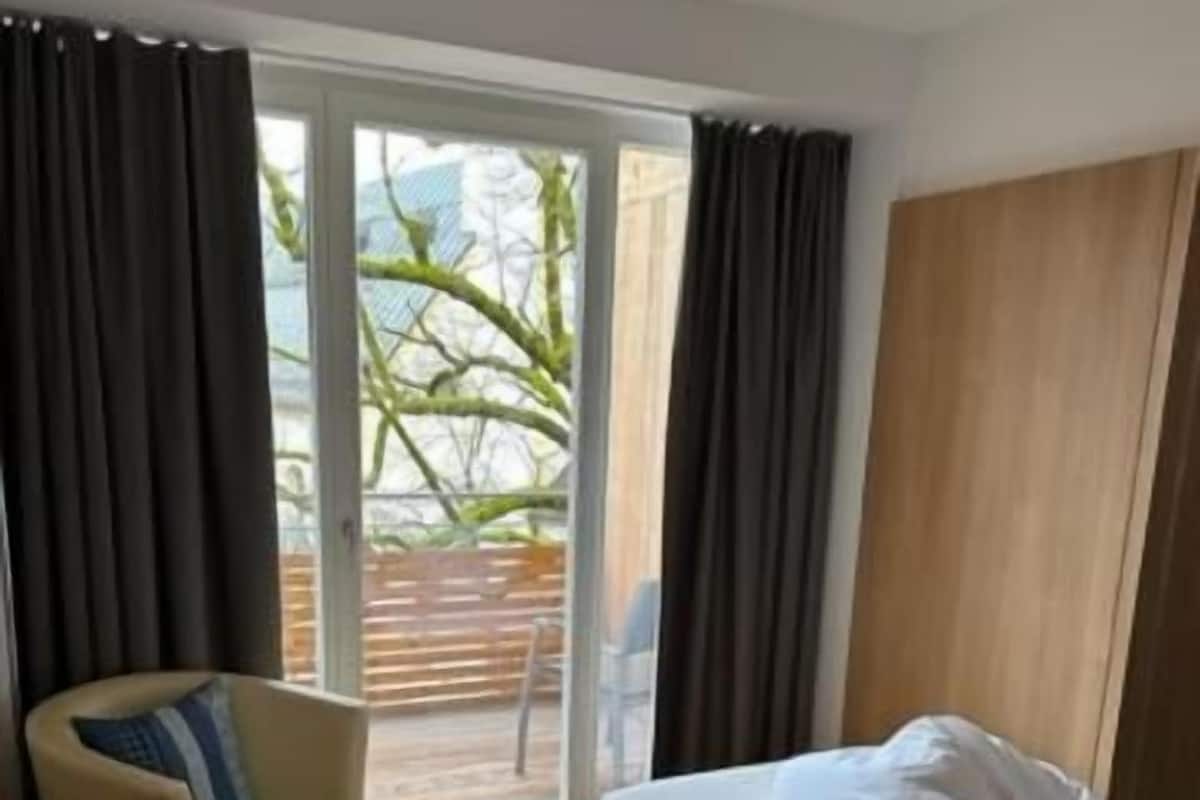 A modern hotel room with a bed, a desk, and a chair.