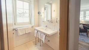 A modern bathroom with a large window, a white sink, and a mirror. - Hotel Kendler (St. Gilgen)