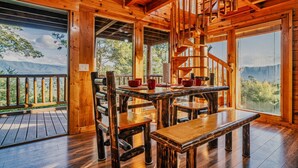 A wooden cabin with a wooden staircase, a dining table with chairs, and a view of mountains. - Perfect Smokies Escape - Park View, Hot Tub & More (Sevierville)