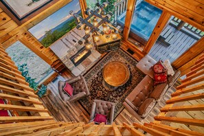 A cozy interior with a fireplace, wooden furniture, and a view of the outdoors. - Perfect Smokies Escape - Park View, Hot Tub & More (Sevierville)