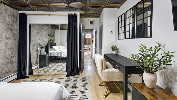 Een moderne slaapkamer met een groot bed, een bureau en een spiegel.
