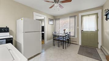 A compact kitchen with a refrigerator, stove, and dining table with chairs.
