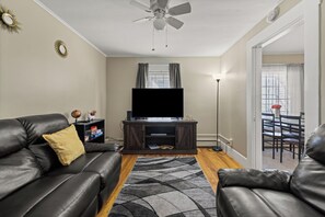 A living room with a leather sofa, a flat-screen TV, a coffee table, and a floor lamp. - The Berlin Basecamp - Where Trails Meet Comfort (Berlin)