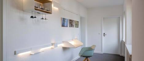 A modern interior with built-in shelves, pendant lights, and a single chair.