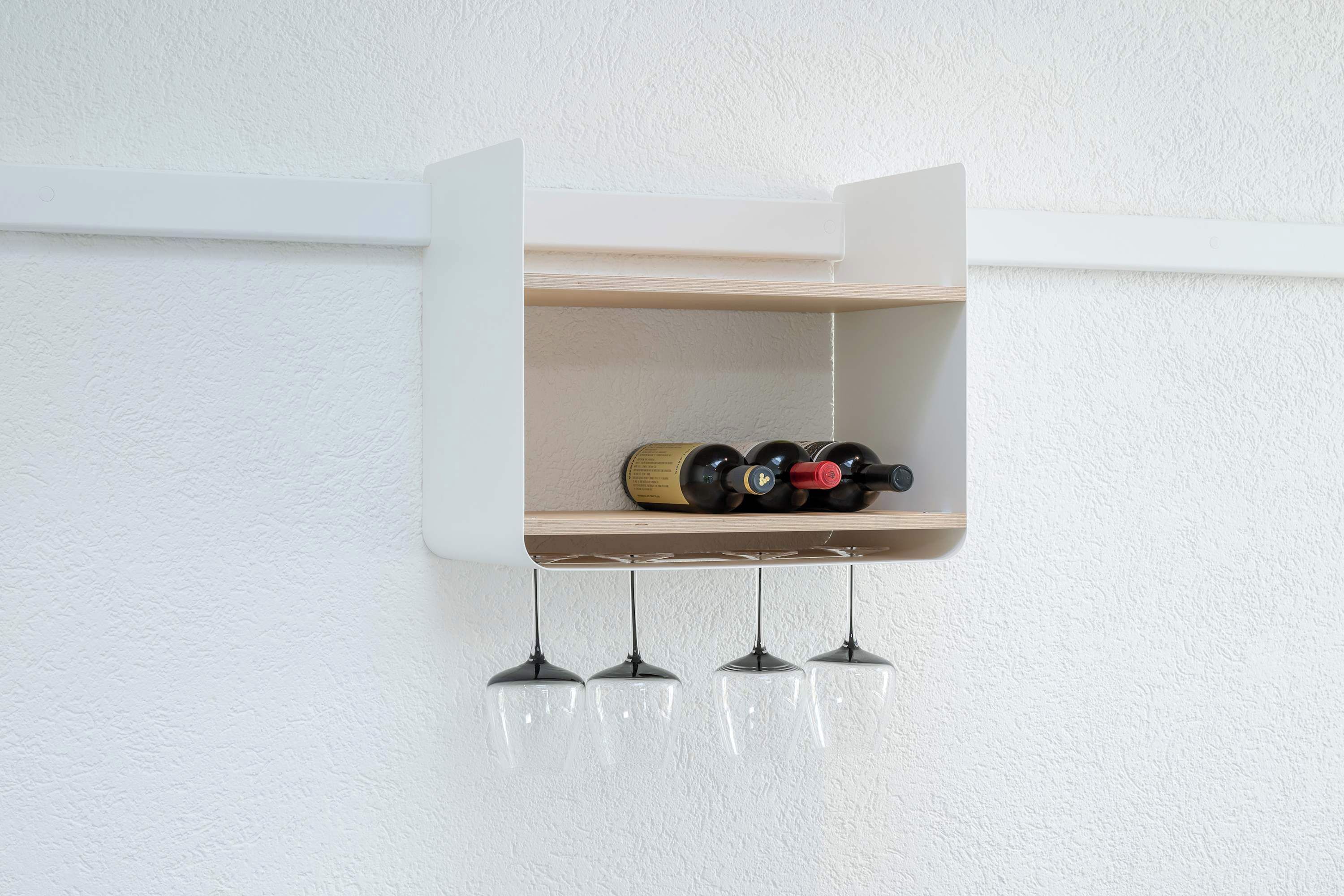 A wall-mounted wine rack with bottles and three hanging wine glasses.