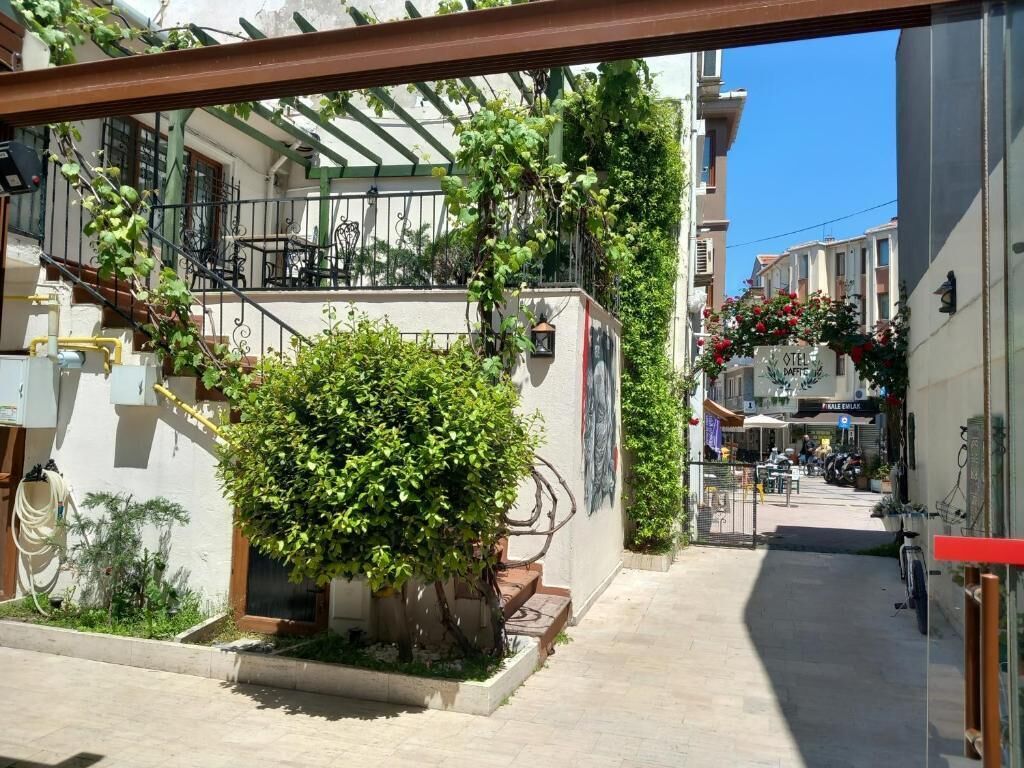 A narrow urban street with a building featuring a small garden and outdoor seating area.