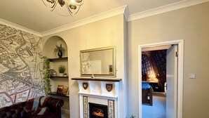 A living room with a fireplace, a map on the wall, a sofa, and a door leading to another room. - New - Chapter House Retreat! 3 minutes walk to The Minster area! (York)