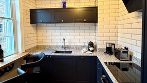 A modern kitchen with dark cabinetry, a granite countertop, a built-in sink, and a hanging light fixture. - New - Chapter House Retreat! 3 minutes walk to The Minster area! (York)