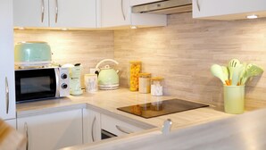 A modern kitchen with white cabinets, a microwave, a kettle, and various kitchen utensils. - Just 50 meters from the Marines de Cogolin beach! (Cogolin)