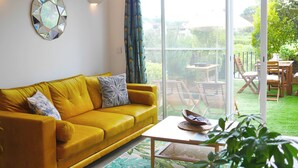 A yellow sofa with patterned cushions, a round mirror, and a table with a bowl and book. - Just 50 meters from the Marines de Cogolin beach! (Cogolin)