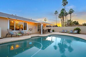 Ein Swimmingpool mit Liegestühlen und einer überdachten Terrasse.