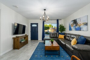 Ein Wohnzimmer mit Fernseher, Holzkonsole, Sofa, Couchtisch und Kunstwerken.